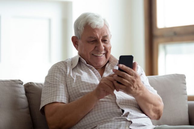 A man in his fifties is sending an international text message