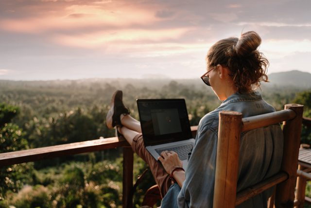 A young women using her laptop in her hotel balcony during her vacation trip abroad  