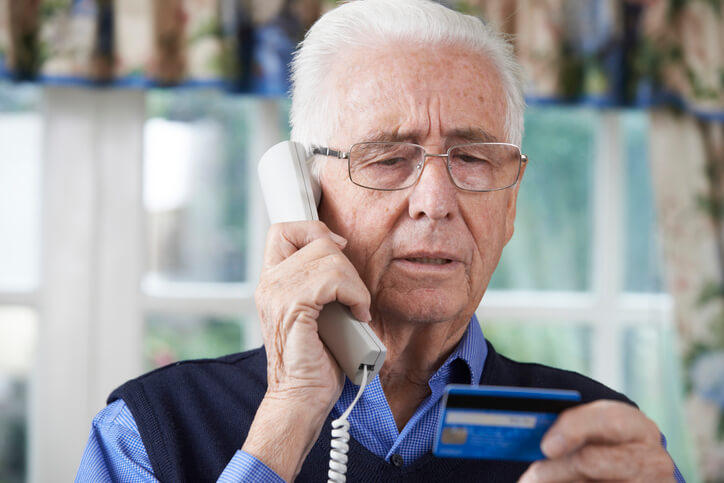 A gray hair old man sending telling his credit card details over the phone
