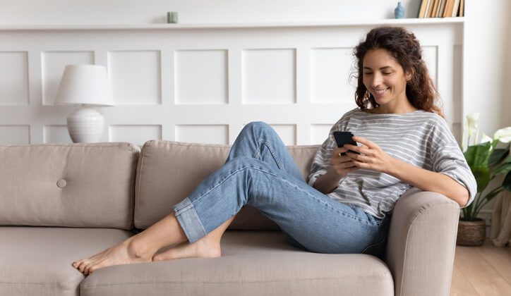 A young girl sitting on her couch comfortably while chatting with her friends using a best chat app