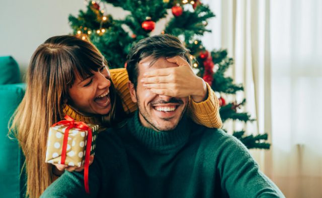 wife surprising husband with Christmas gift