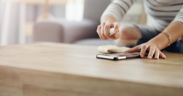 Cropped shot of an unrecognizable woman cleaning her device screen at home