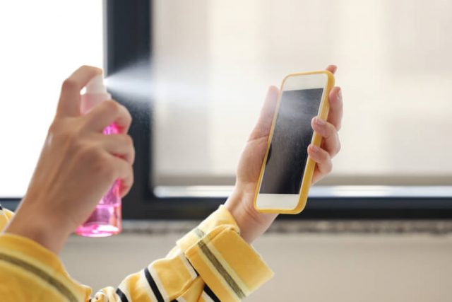 Woman disinfecting her mobile phone