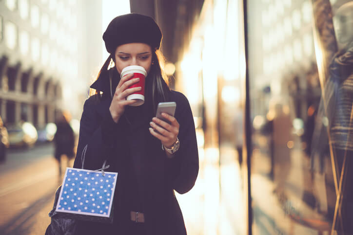 a women reading Christmas message on mobile while sipping coffee