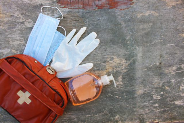 First aid kit on wooden background. Concept of protect yourself from COVID-2019. Top view. travel essentials