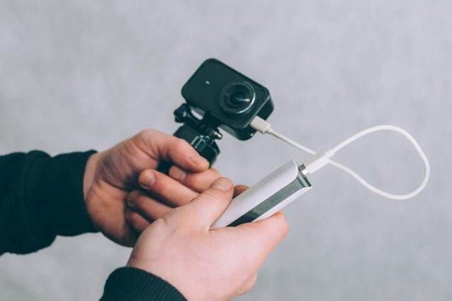 A man is charging an action camera with a portable charger