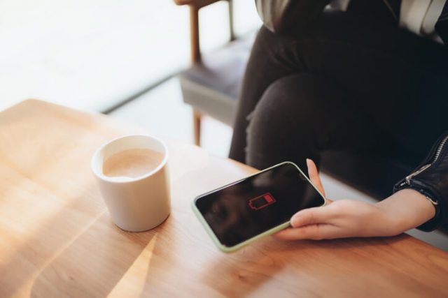 Woman holding a smartphone battery drained and thinking about how to increase phone battery life