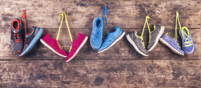 travel essentials pairs of various running shoes hang on a nail on a wooden fence background