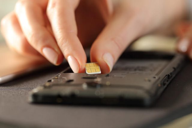 Closeup of woman hands putting sim card on smart phone with sim only vs contract deal