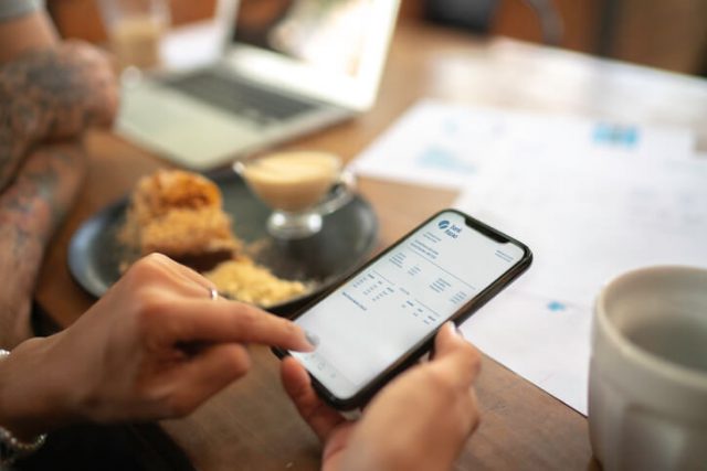 Woman checking account statement of her digital investment on her mobile phone using money saving app