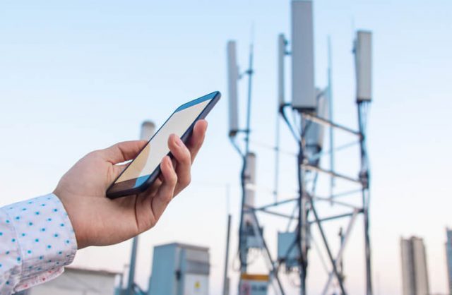 5G communications tower with man using mobile phone signals