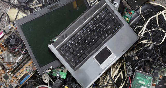 Broken laptop computer on a pile of electronic waste ewaste