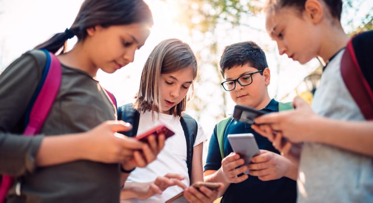 Group of kids playing video games on smart phone after school