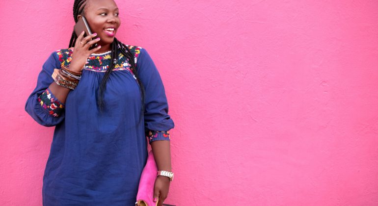 Shot of a mature african woman in casuals standing by a pink wall and calling to zimbabwe