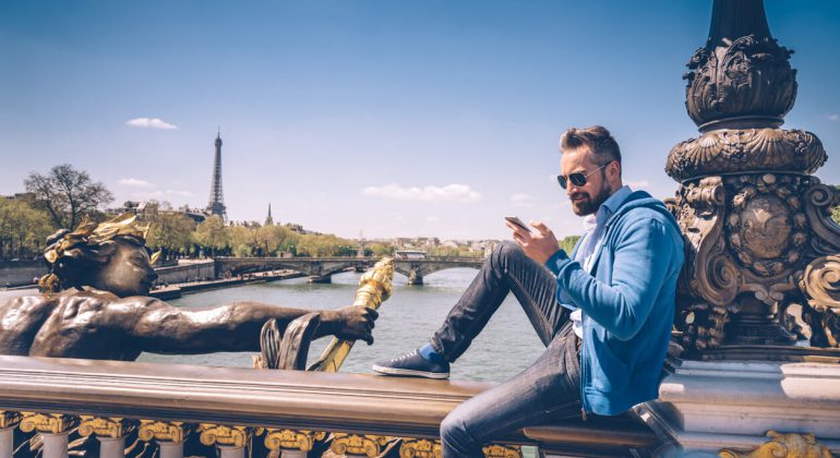 bearded man with mobile sitting on Pont Alexandre in paris bearded man with mobile sitting on Pont Alexandre rading how to make cheap calls in france