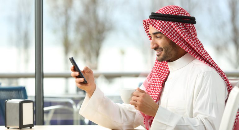 Side view of an arab man texting in a smart phone calling saudi arabia